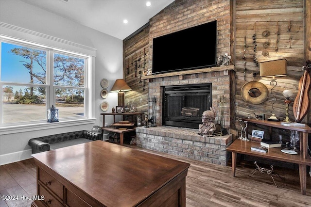 living room featuring a brick fireplace, vaulted ceiling, and wood-type flooring