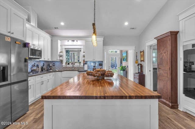 kitchen with stainless steel appliances, butcher block countertops, white cabinetry, and a center island