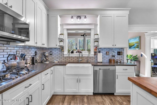 kitchen with sink, butcher block counters, white cabinets, backsplash, and appliances with stainless steel finishes