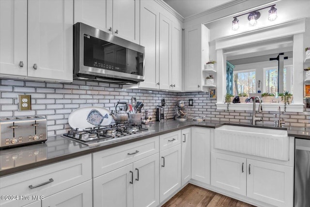 kitchen with white cabinetry, appliances with stainless steel finishes, decorative backsplash, sink, and light hardwood / wood-style flooring