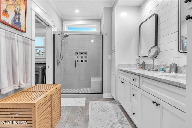 bathroom featuring a shower with door, crown molding, and vanity