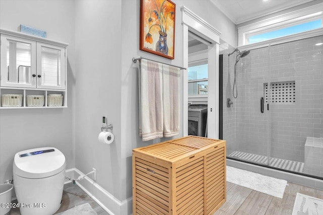 bathroom featuring washer / clothes dryer, a shower with shower door, and toilet