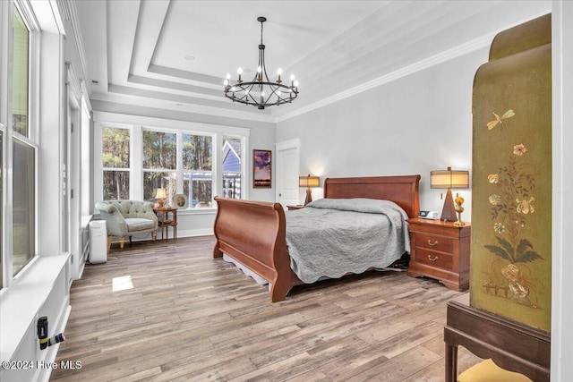 bedroom with light hardwood / wood-style floors, ornamental molding, a raised ceiling, and a chandelier