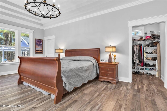 bedroom featuring a closet, ornamental molding, a notable chandelier, and dark wood-type flooring