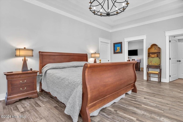 bedroom featuring wood-type flooring, ornamental molding, and a notable chandelier