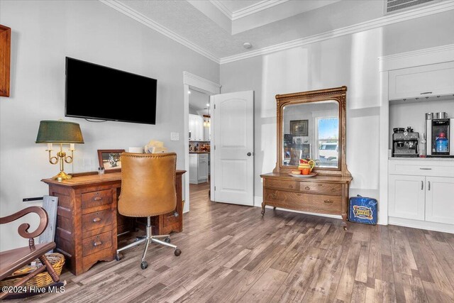 office area with hardwood / wood-style floors, crown molding, and a tray ceiling