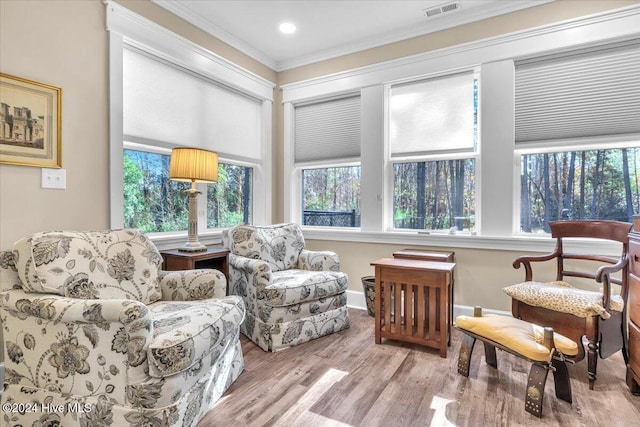 living area featuring crown molding, light hardwood / wood-style flooring, and a healthy amount of sunlight