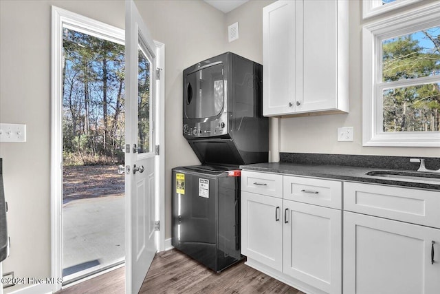 kitchen with white cabinets, dark wood-type flooring, stacked washer / drying machine, and sink