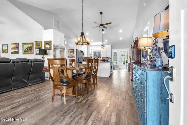 dining room featuring ceiling fan with notable chandelier, high vaulted ceiling, and light hardwood / wood-style flooring