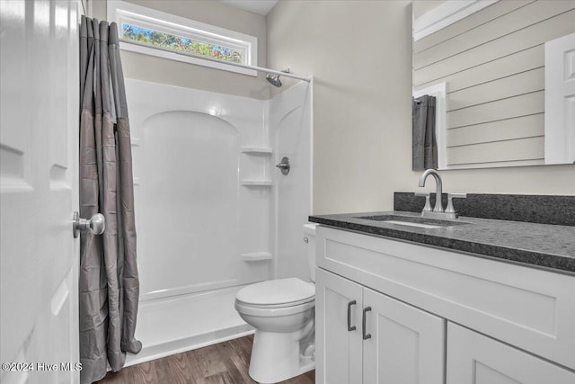 bathroom with toilet, wood-type flooring, walk in shower, and vanity