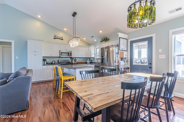 dining area with high vaulted ceiling, dark wood-type flooring, and a notable chandelier