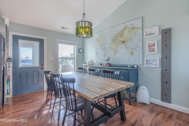 dining space with lofted ceiling, dark hardwood / wood-style floors, and a notable chandelier