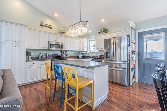 kitchen featuring a breakfast bar, dark wood-type flooring, white cabinets, hanging light fixtures, and appliances with stainless steel finishes