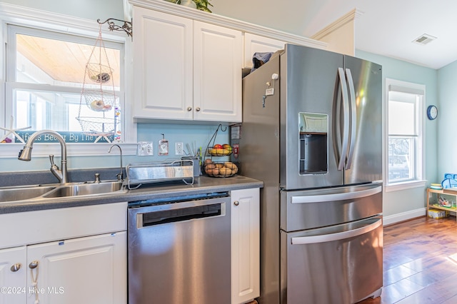 kitchen with stainless steel appliances, white cabinetry, plenty of natural light, and sink