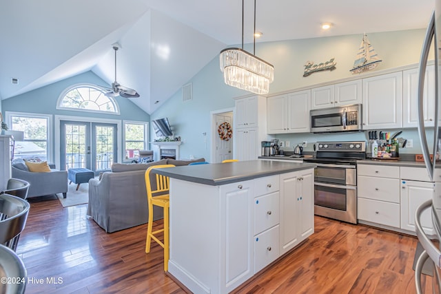 kitchen with stainless steel appliances, high vaulted ceiling, dark hardwood / wood-style floors, white cabinets, and ceiling fan with notable chandelier