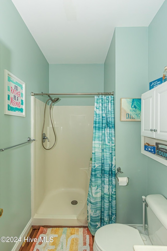 bathroom with hardwood / wood-style flooring, toilet, and walk in shower