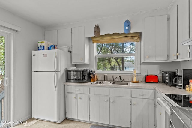 kitchen with electric range, white fridge, white cabinetry, and sink