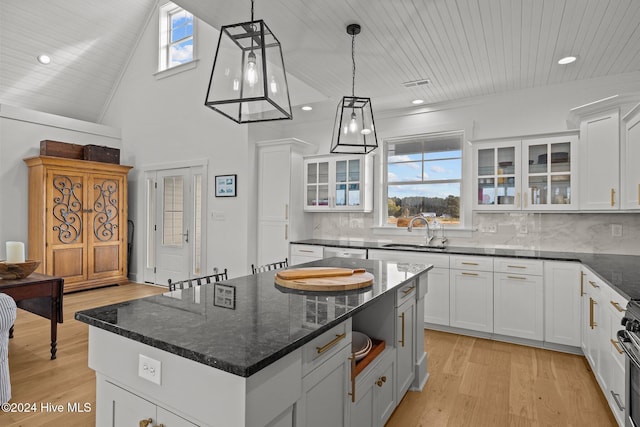 kitchen featuring a kitchen island, white cabinetry, sink, and hanging light fixtures