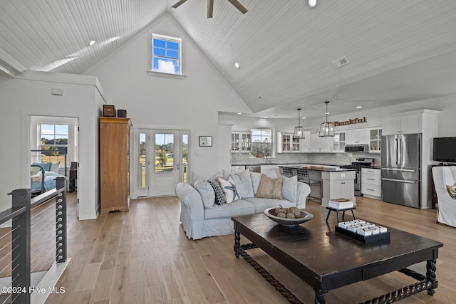 living room featuring ceiling fan, plenty of natural light, high vaulted ceiling, and light wood-type flooring