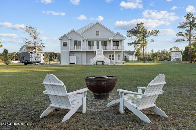 rear view of house featuring an outdoor fire pit and a lawn