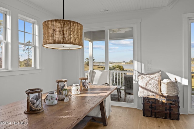 dining space with a wealth of natural light, crown molding, and light wood-type flooring