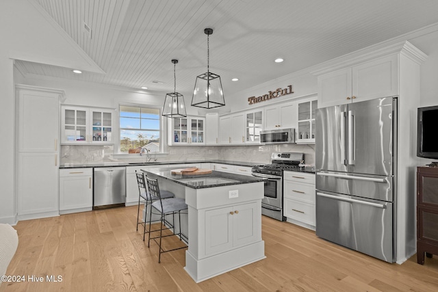 kitchen with stainless steel appliances, sink, light hardwood / wood-style floors, a kitchen island, and hanging light fixtures