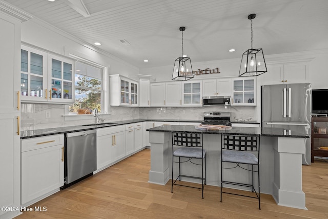 kitchen with appliances with stainless steel finishes, light wood-type flooring, a kitchen island, and a breakfast bar area