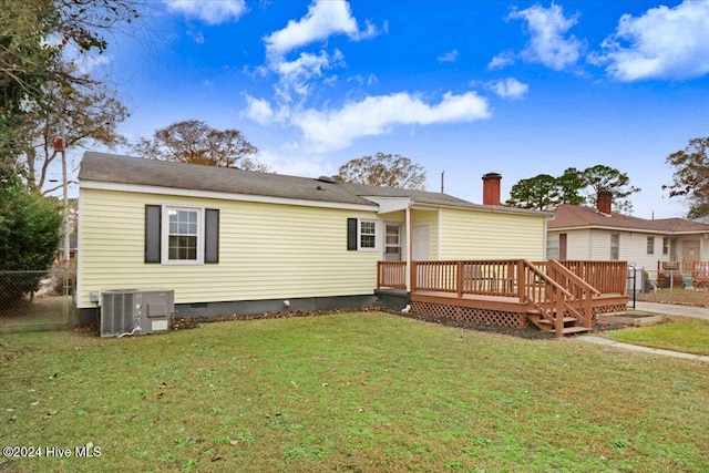 rear view of property featuring central air condition unit, a wooden deck, and a lawn