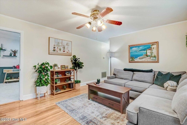 living room featuring ceiling fan, ornamental molding, and light wood-type flooring