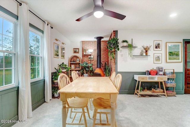 dining room featuring light carpet, a wood stove, and ceiling fan