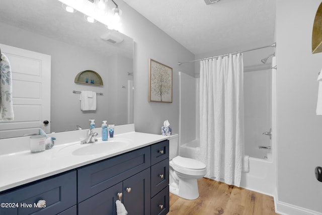 full bathroom featuring hardwood / wood-style floors, vanity, toilet, a textured ceiling, and shower / tub combo