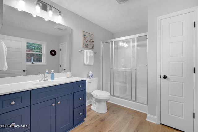 bathroom with a textured ceiling, vanity, hardwood / wood-style flooring, toilet, and a shower with shower door