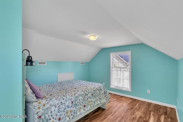 bedroom with wood-type flooring and vaulted ceiling