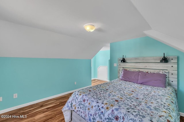 bedroom featuring hardwood / wood-style floors and vaulted ceiling