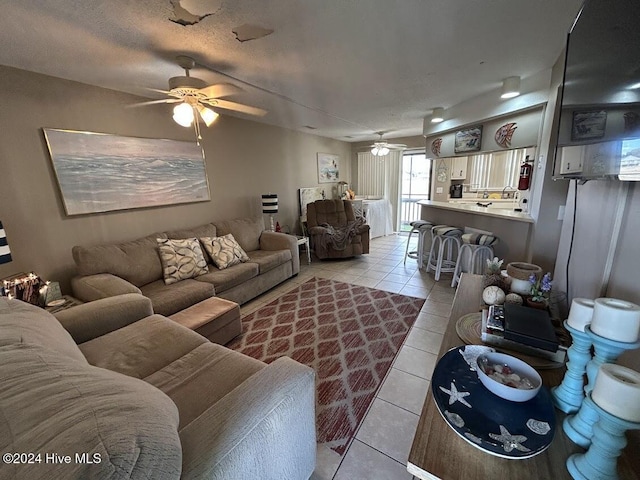 living room with ceiling fan, light tile patterned flooring, and a textured ceiling