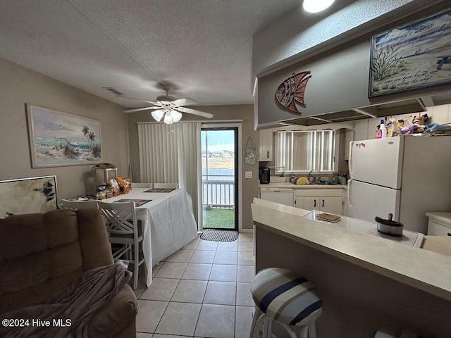 kitchen with white cabinetry, sink, a textured ceiling, white appliances, and light tile patterned floors