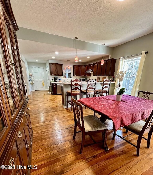 dining room featuring light wood-type flooring and a textured ceiling