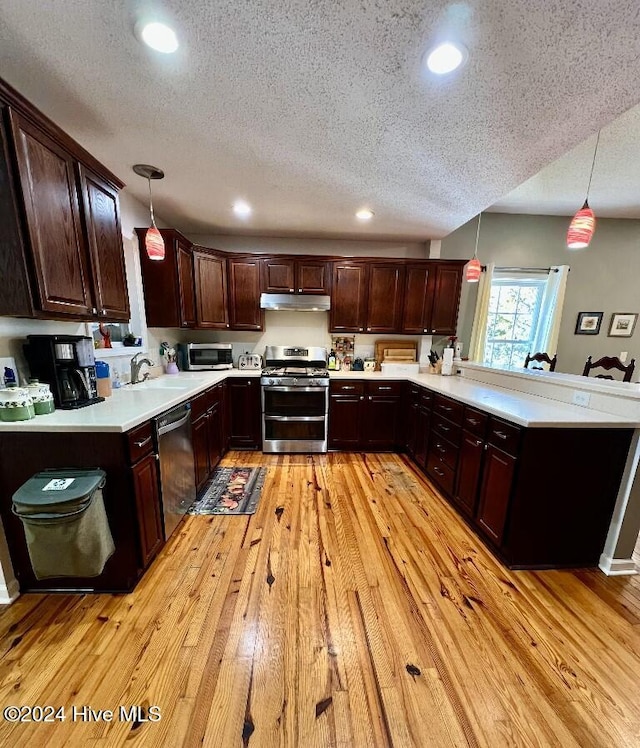 kitchen featuring light hardwood / wood-style floors, hanging light fixtures, a textured ceiling, and appliances with stainless steel finishes