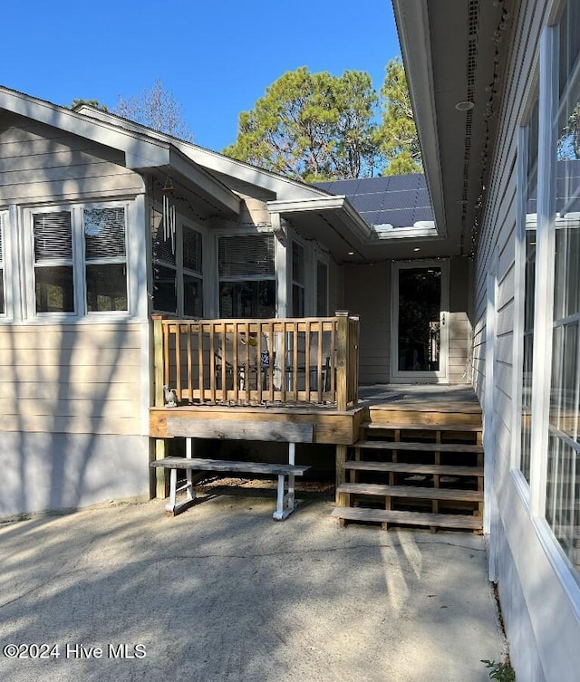 doorway to property featuring solar panels and a wooden deck