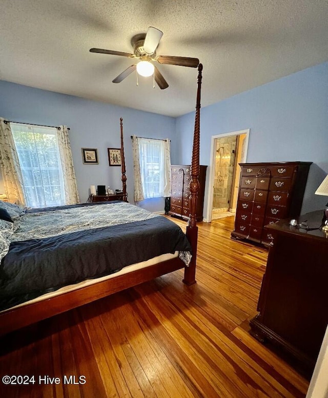 bedroom with ensuite bath, ceiling fan, wood-type flooring, and a textured ceiling