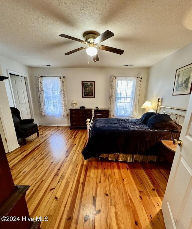 bedroom featuring ceiling fan, light hardwood / wood-style floors, and a textured ceiling