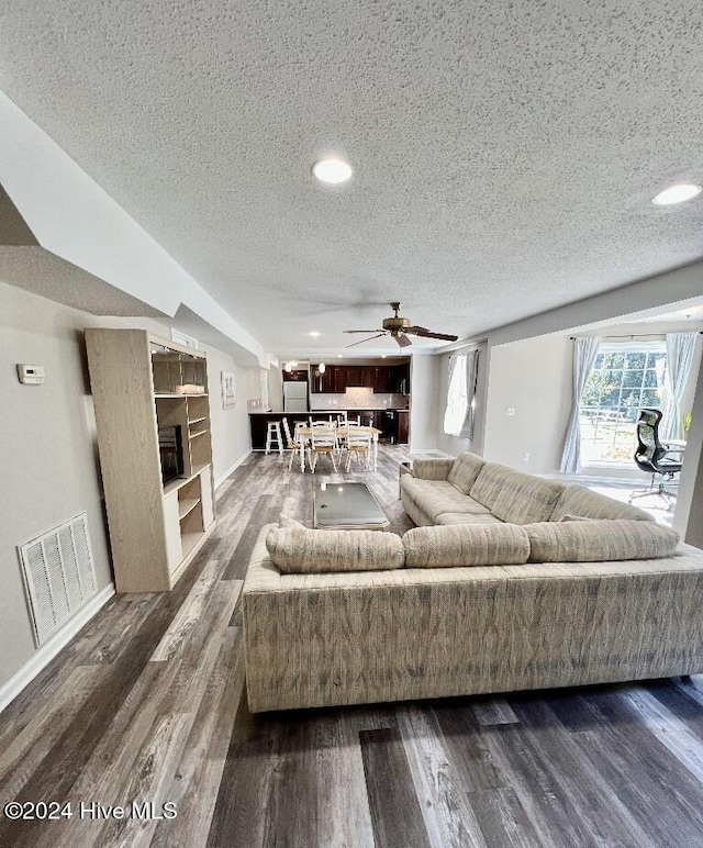 living room featuring a textured ceiling, dark hardwood / wood-style flooring, and ceiling fan