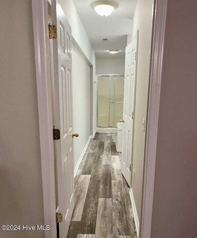 hall featuring a textured ceiling and dark hardwood / wood-style floors