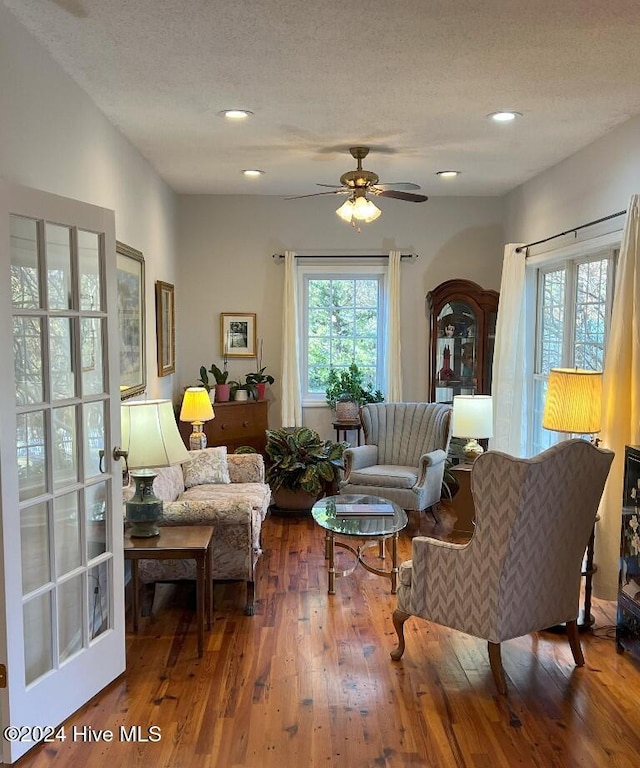 living area featuring wood-type flooring, a textured ceiling, and ceiling fan