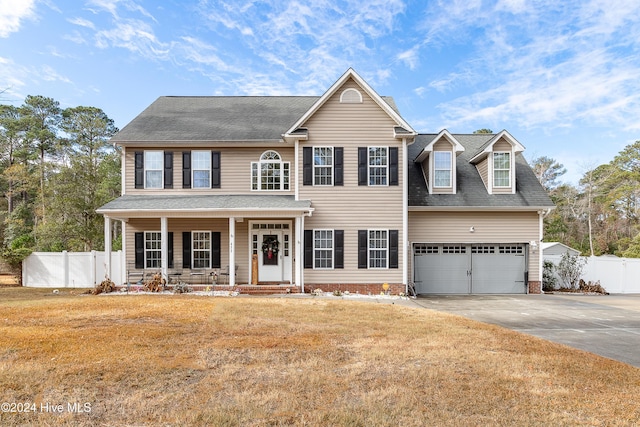 colonial house featuring a front yard, a porch, and a garage