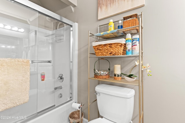 bathroom featuring toilet and bath / shower combo with glass door