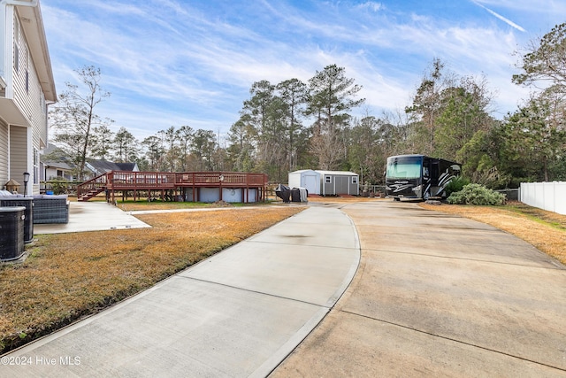 view of yard featuring a shed, a deck, and central air condition unit