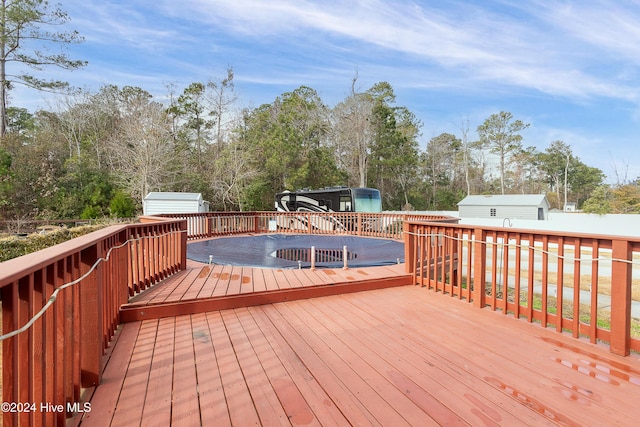 wooden deck with a covered pool and a storage unit