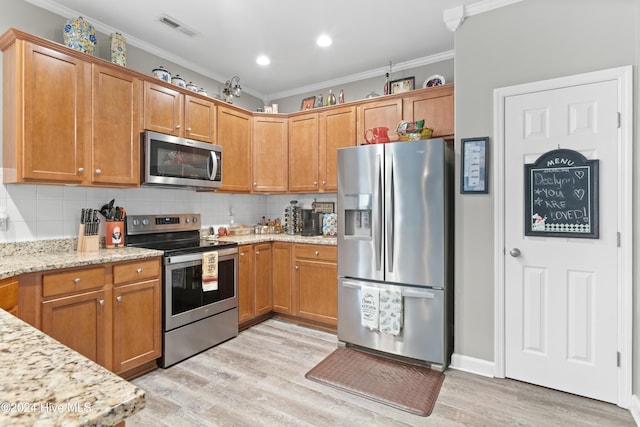 kitchen with stainless steel appliances, light stone counters, crown molding, and light hardwood / wood-style floors