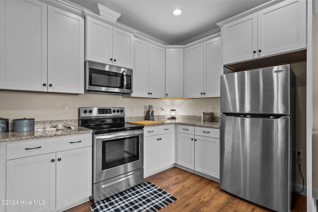 kitchen with white cabinets, appliances with stainless steel finishes, light stone counters, and wood-type flooring